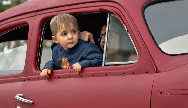Kind sitz auf Beifahrersitz und guckt aus rotem Auto